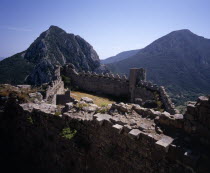 Chateau Puilarens.  Ruined medieval Cathar castle stronghold set high on limestone cliff.  View looking down on battlements from the keep to mountain peaks beyond.