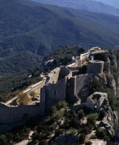 Chateau Peyrepertuse.  Ruined medieval Cathar castle stronghold  lower section situated on steep rocky mountainside high above surrounding landscape.