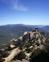 Chateau Peyrepertuse.  Ruined medieval Cathar castle stronghold  lower section seen from upper castle.  Fortified walls and turrets along crest of hill.