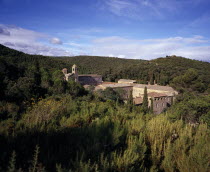 Fontfroide.  Rooftops and bell tower of former Cistercian Abbey among cypress and other trees.  The remaining buildings date from the twelth century.