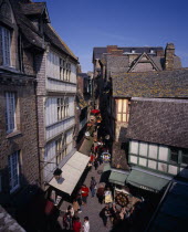 Looking down on narrow street  souvenir arcade and shoppers from outer wall footway.