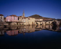 Saint-Antonin-Noble.  Village houses  church spire and bridge reflected in water of the River Aveyron.