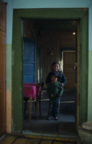 Brother and sister standing in open doorway of home with green painted door frame.