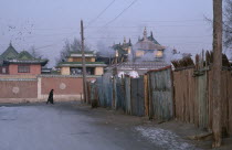 Gandan Monastery.  View along street towards monastery rooftops with passing figure wearing winter coat and hat.