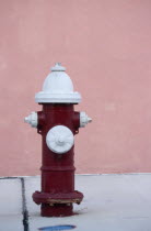 Fire Hydrant on pavement near a pink wall