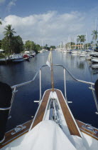 View of Canal from boats bow with yachts moored outside waterfront houses along waterway