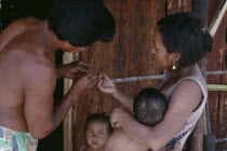 Makuna family.  Venancio removing thorn from his wifes finger with two young children partly seen.Tukano  Makuna Indian North Western Amazonia American Colombian Columbia Hispanic Indegent Kids Latin...