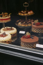 Display of cakes and pastries in window.