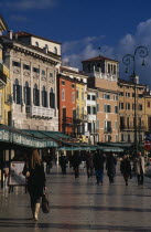 Piazza Bra.  People walking past line of bars and cafes and painted facades of architecture overlooking square.