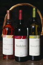 Bardolino.  Bottles of red  white and rose wine from the Bardolino region displayed in front of basket and framed by handle.