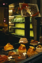 Cakes and chocolate displayed in window of cafe.