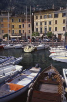 Gargnano.  Waterside buildings with boats moored in harbour in the foreground.