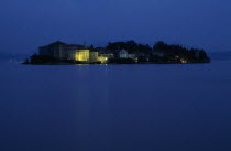 Borromeo Islands.  View across lake towards small rocky island of Isola Bella with Palazzo Borromeo illuminated at night.