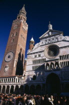 Piazza del Comune.  Part view of Duomo facade and medieval bell tower known as the Torrazzo linked by a Renaissance loggia.  Crowds of visitors in foreground.