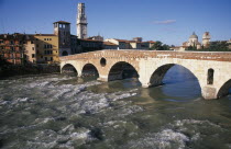 Bridge across the River Adige with city buildings  tiled and domed rooftops beyond.