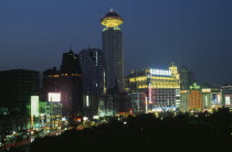 Renmin Square or the People s Square at night  with buildings illuminated with coloured lights and neon advertising.