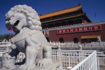 Entrance gateway to the Forbidden City from Tiananmen Square with portrait of Mao on exterior wall and stone statue of lion in foreground.