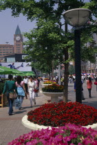 Wangfujing street with crowds of shoppers lined with trees  street lamps and raised circular flower beds.