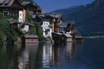 Typical architecture and boat houses on shore of Hallstattersee Lake and reflected in rippled surface.