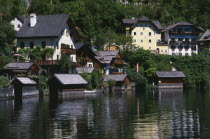 Typical architecture and boat houses on shore of Hallstattersee Lake and reflected in rippled surface.