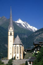 Austria, Hohe Tauern Karnten, High Tauern National Park  Heiligenblut, Parish church of St Vincent with snow capped Grossglockner peak behind.