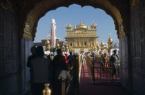 Entrance arch to the Golden Temple with people walking along red carpet