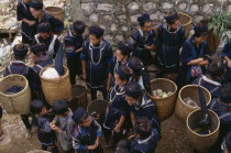 Muong tribes people carrying woven panniers at market.