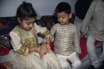 Young girl tying a thread to the wrist of a young boy during the Sacred Thread ceremony. The Hindu male rite of passage ceremony