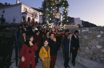 Christmas procession through village carrying garlanded statue of the Virgin and Child.