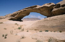 Rock formation in the form of natural arch framing view to distant flat topped rock