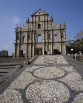 Church remains with statues in recessed arches and mosaic path