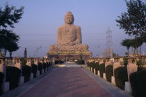 Giant seated Buddha statue seen from pathway leading up to the base.