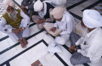 Group of Sikh men sitting on black and white marble floor of Golden Temple complex to read holy book.Asia Asian Bharat Inde Indian Intiya Male Man Guy Religion Religion Religious Sihism Sikhs