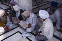 Group of Sikh men reading from holy book on black and white marble floor of the Golden Temple complex.Asia Asian Bharat Inde Indian Intiya Male Man Guy Religion Religion Religious Sihism Sikhs