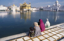 Three women and children sitting on marble walkway beside the sacred pool looking towards The Golden Temple.3 Asia Asian Bharat Female Woman Girl Lady Inde Indian Intiya Kids Religion Religious