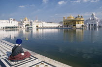 Sikh man sitting on marble walkway beside the sacred pool surrounding the Golden templeAsia Asian Bharat Inde Indian Intiya Male Men Guy One individual Solo Lone Solitary Religion Religion Religious...