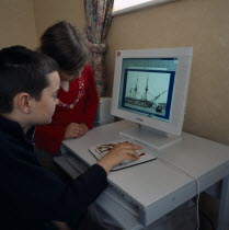 Young boy and girl sitting at a home computer looking at educational web site with image of HMS Victory on the screen.