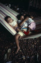 Three young children sleeping in hammock.