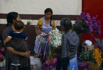 Woman vendor and customers at flower market stall.American Female Women Girl Lady Hispanic Kids Latin America Latino Mexican Female Woman Girl Lady