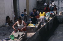 Women scrubbing clothes in communal wash place.