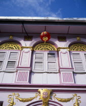 Pink and gold painted shopfront with wooden window shutters and red and gold Chinese lantern hanging from the roof for Chinese New Year.Asian Malaysian Southeast Asia