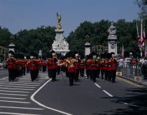 Pageantry Marching guards band with The Victoria Memorial behind. Union Jack flags and tourists watching from pavement