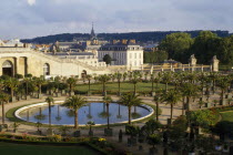 General view over round pool surrounded by palms with the town behind