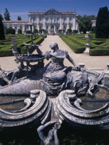 Palacio Nacional de Queluz facade with fountain statue in the foreground and formal gardens.