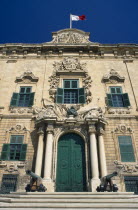 Auberge de Castille et Leon. Decorative baroque facade with steps leading to green doorway flanked by pillars and cannons with the Maltese flag flying from roof. Official residence of the Prime Minister