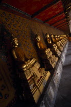 Wat Arun. Golden seated Buddha statues in cloister of Ordination Hall.