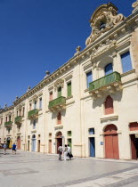 People walking by the waterfront redevelopment of old Baroque Pinto wharehouses below the bastion walls of Floriana beside the cruise ship terminal