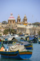 Fishing village harbour on the south coast with colourful Kajjiki fishing boats and the Church dedicated to Our Lady of the Rosary The Madonna of Pompeii