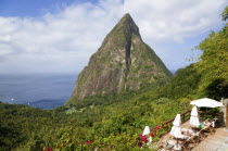 Val des Pitons The volcanic plug of Petit Piton and the lush valley seen from the sun deck of the Ladera Spa Resort Hotel with tourists sunbathing on sunbeds beside umbrellas