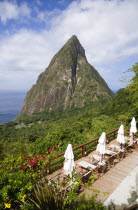 Val des Pitons The volcanic plug of Petit Piton and the lush valley seen from the sun deck of the Ladera Spa Resort Hotel with tourists sunbathing on sunbeds beside umbrellas